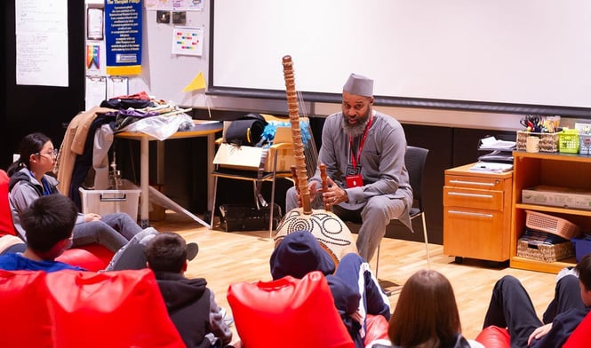 The performer Baby the Storyteller performs with a musical instrument at ISB