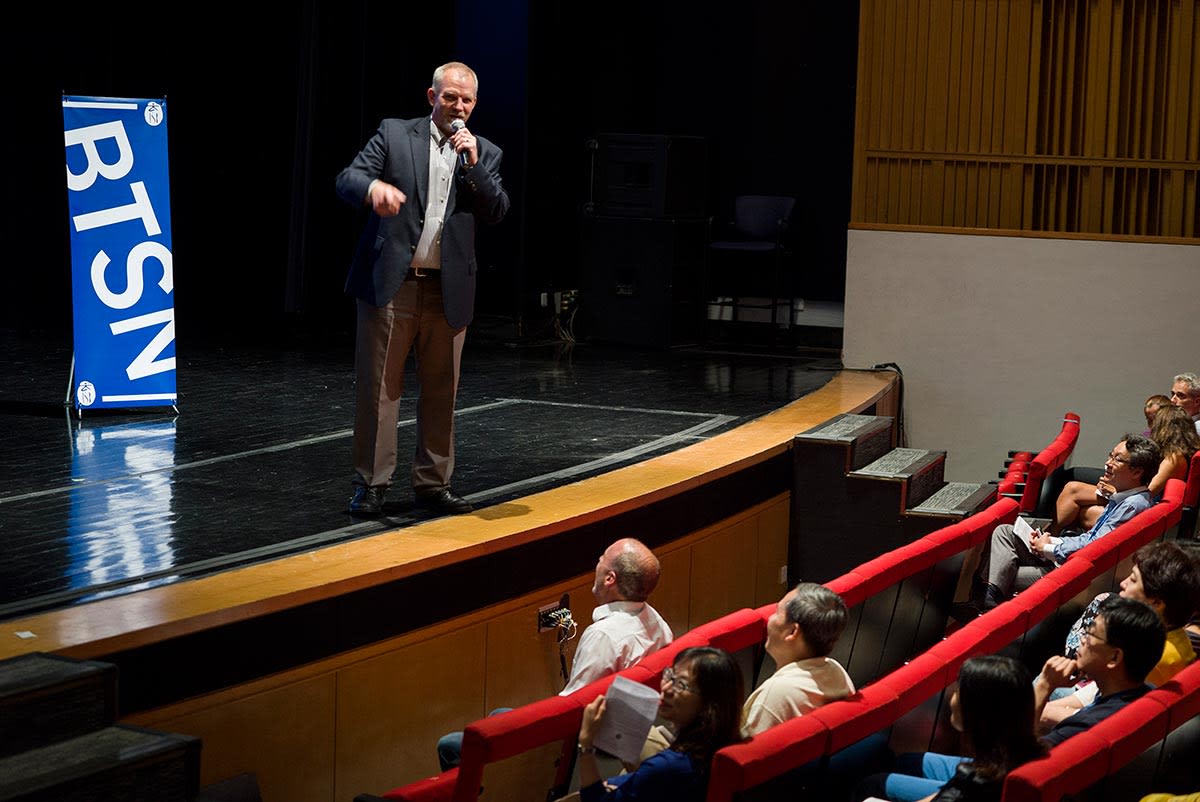 Jon Hill, ISB's Middle School Principal, addresses parent from the stage at a Back to School Night