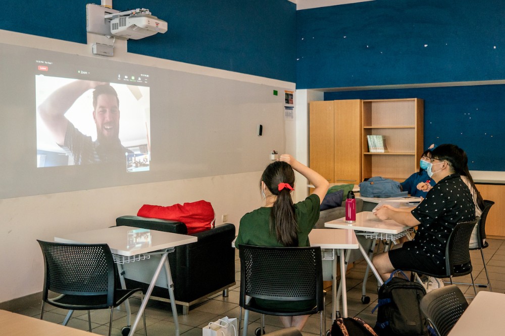 A classroom with teacher Owen Fidler projected on screen