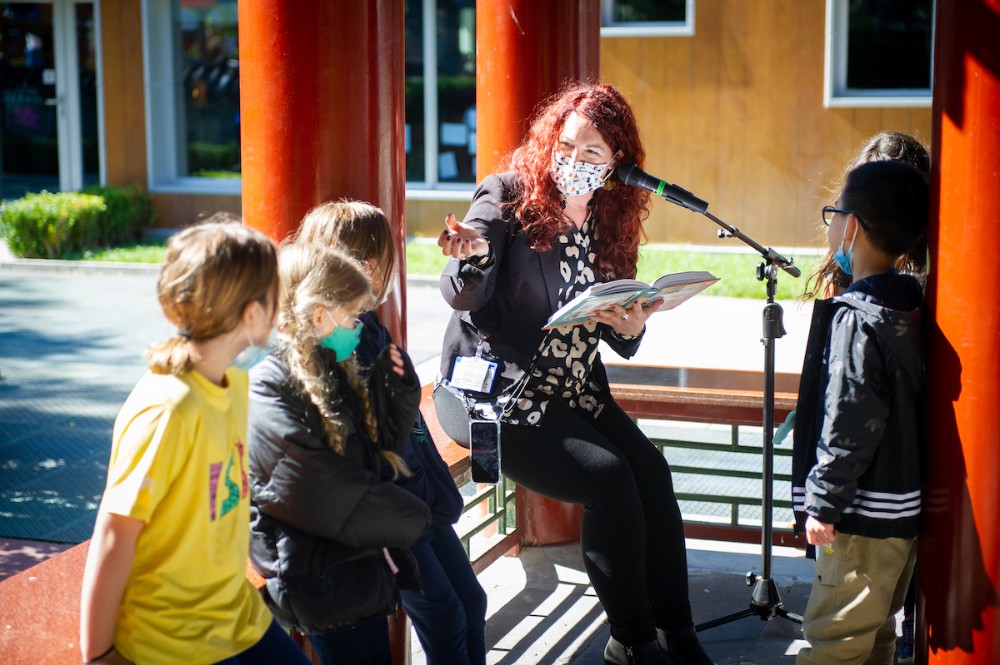 A teacher reads to Elementary School students in a bandstand
