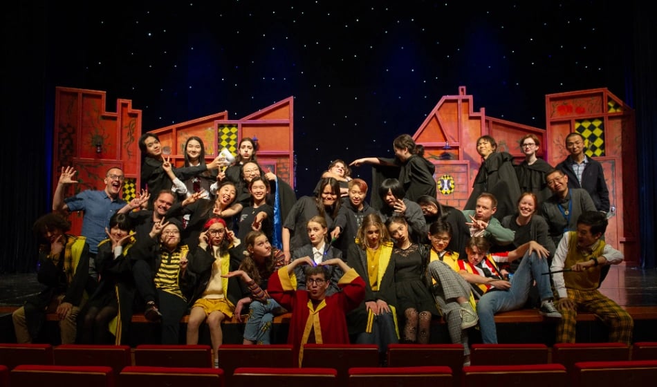 The cast and crew from Puffs pose for a group shot on stage