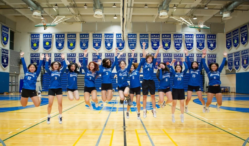 The girls HS volleyball team leap in unison for a team photo