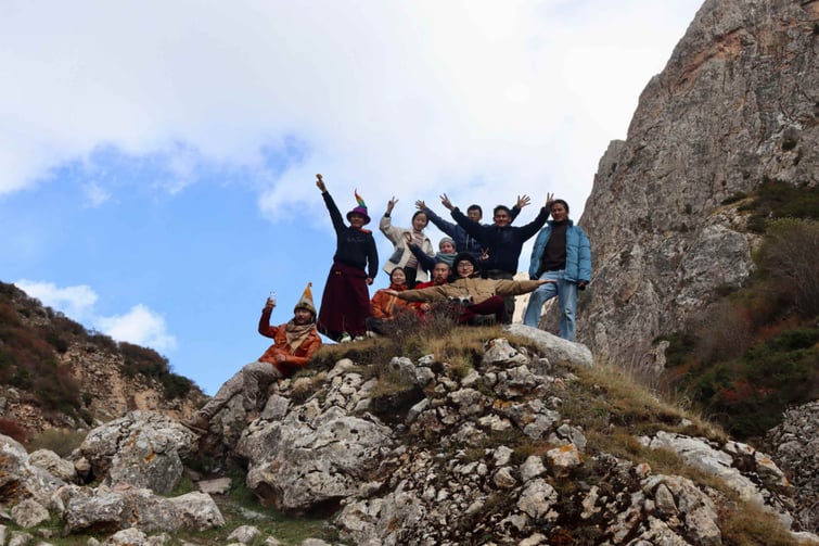 A group of ISB students and people in traditional Chinese ethnic dress on a peak in the countryside