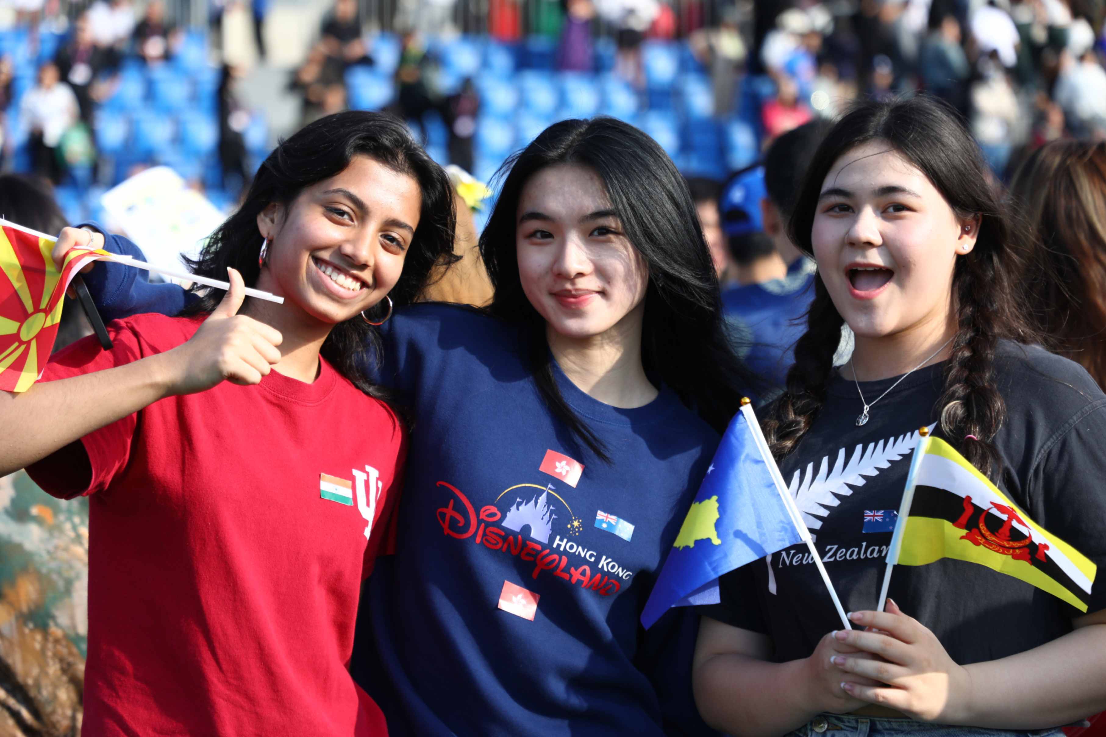 Three students pose with flags at ISB's International Day