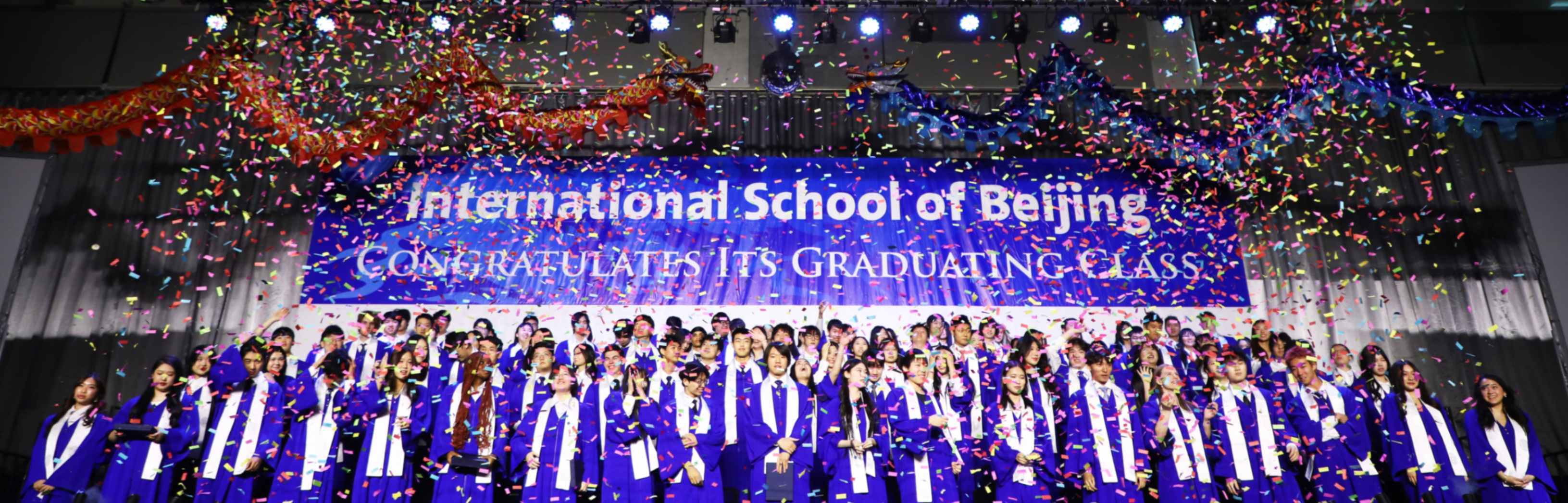 A group shot of ISB's Class of 2025 dressed in graduation gowns and throwing their caps in the air